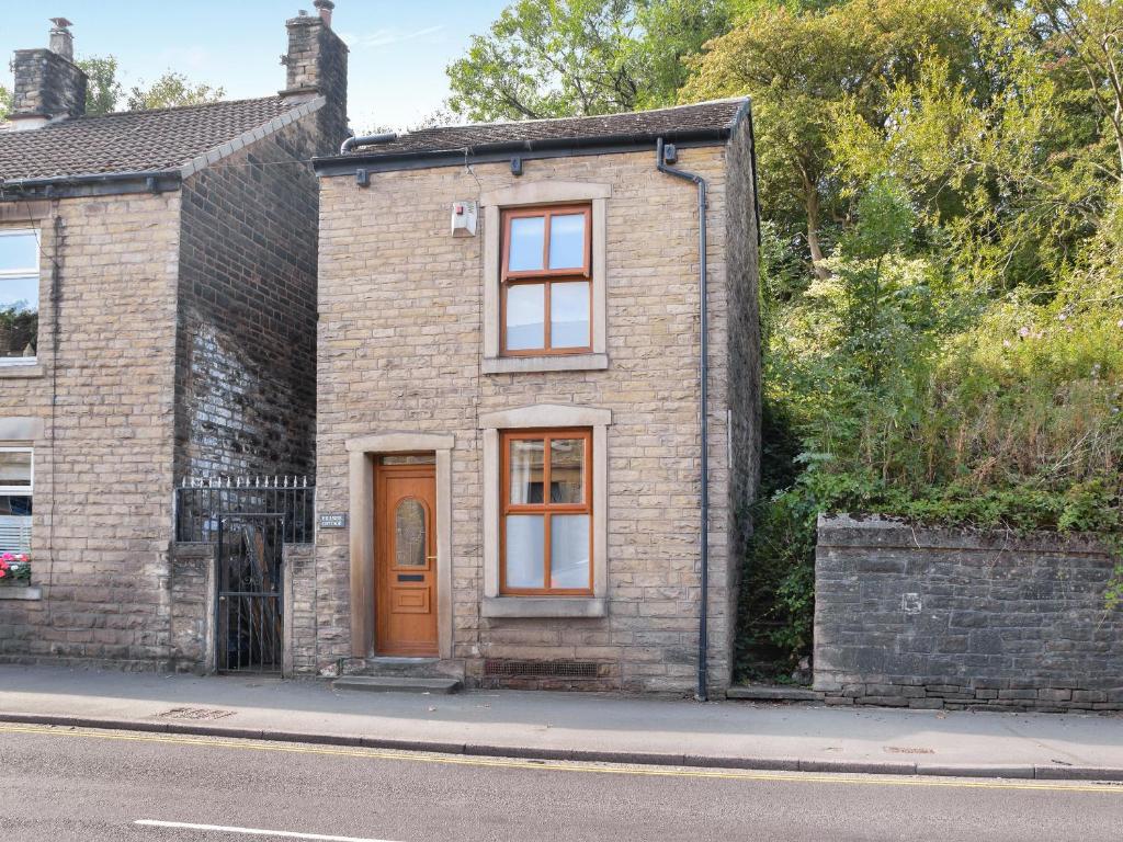 ein Backsteinhaus mit einer Holztür auf einer Straße in der Unterkunft Hillside Cottage in Glossop