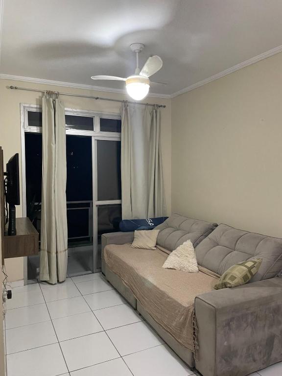 a living room with a couch and a window at Enseada apartment accommodates up to 8 people in Guarujá