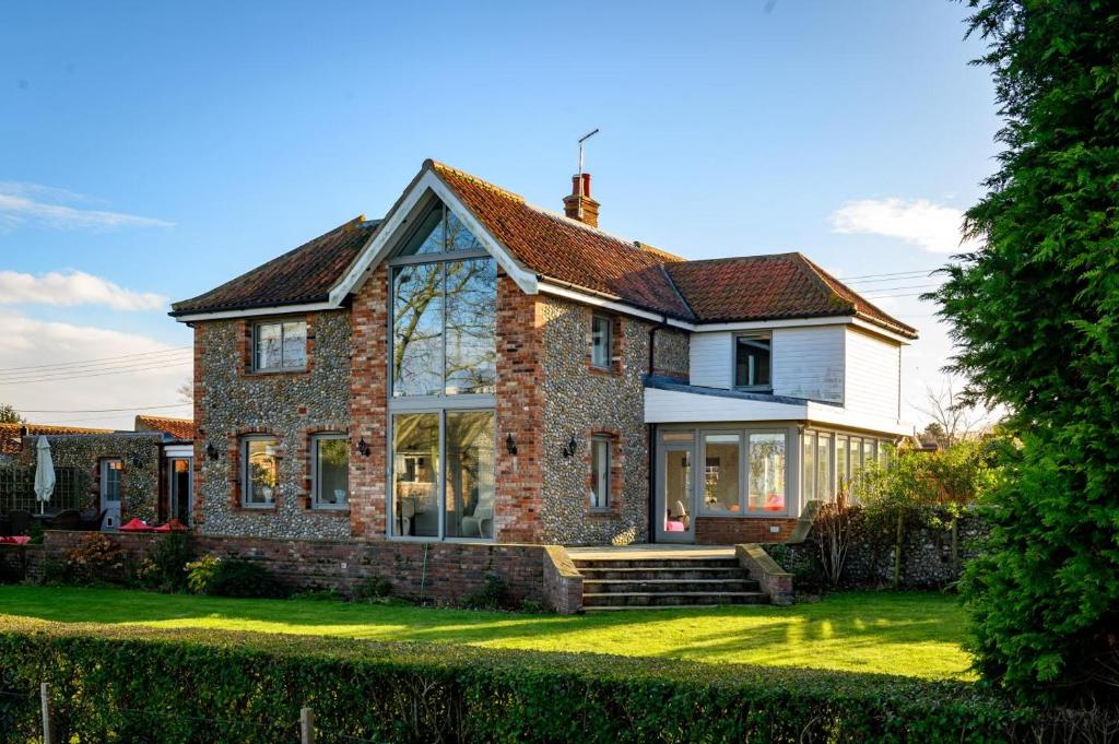 a brick house with large windows on a lawn at Vine Cottage in Blakeney