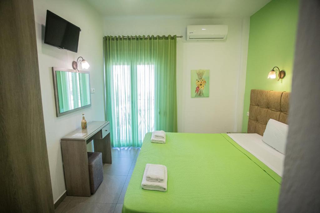 a green bedroom with a large bed and a television at Studios Nopi-Zoi in Skiathos