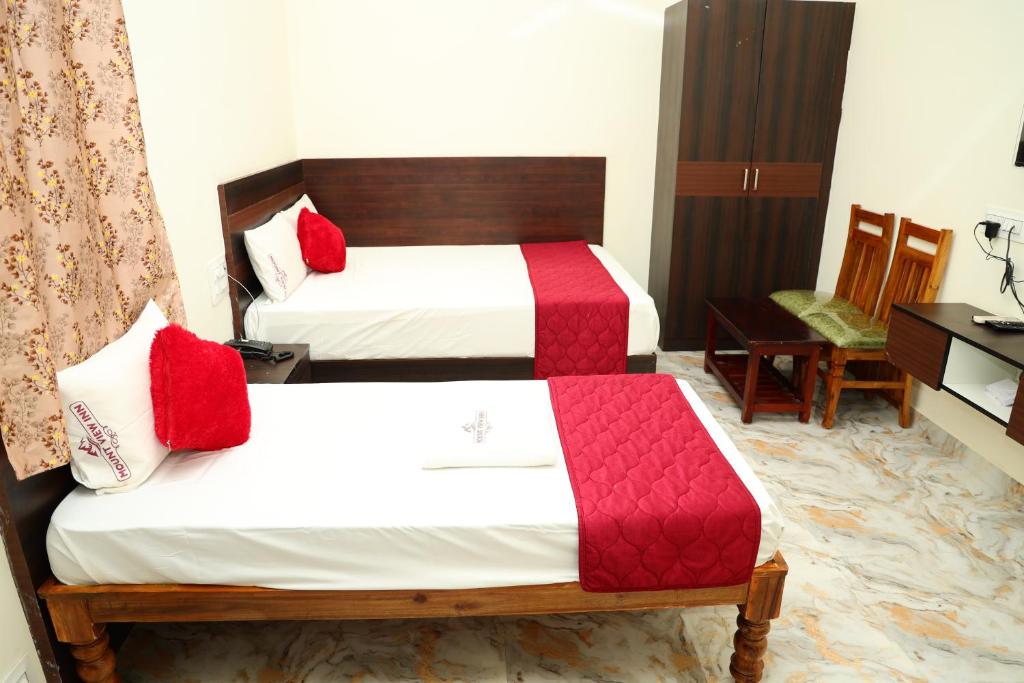 a bedroom with two beds with red and white sheets at Mount View Inn in Krishnagiri