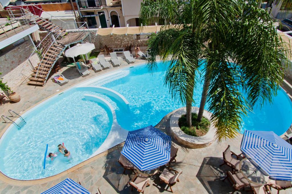 an overhead view of a swimming pool with umbrellas and a palm tree at Ionion Star Hotel in Lefkada