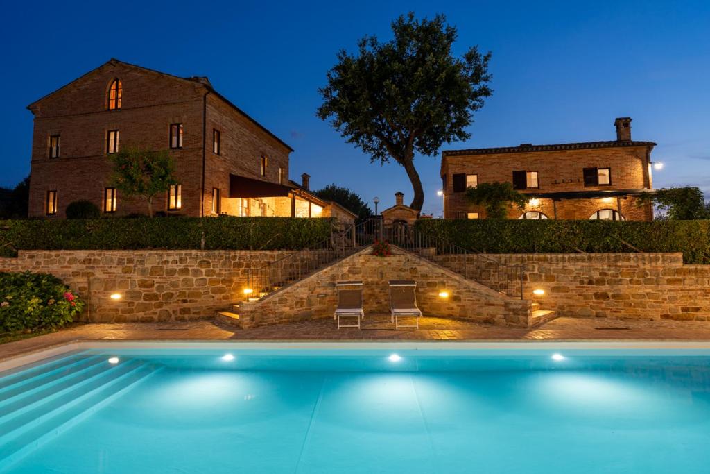 a house with a swimming pool in front of a house at Collerovere Country House in SantʼAngelo in Pontano