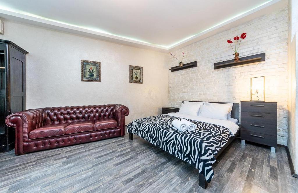 a bedroom with a bed and a leather couch at Уютная квартира с джакузи в центре Киева in Kyiv