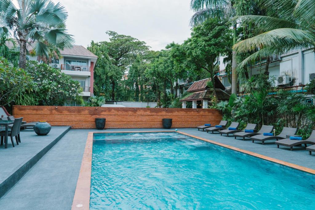 A rectangular outdoor pool surrounded by loungers and tropical planting.