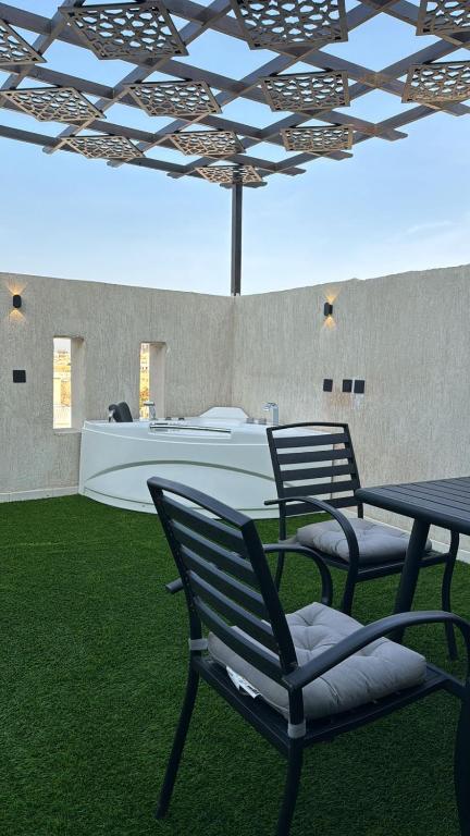two chairs and a table in a room with grass at شاليه الهنا in Jeddah
