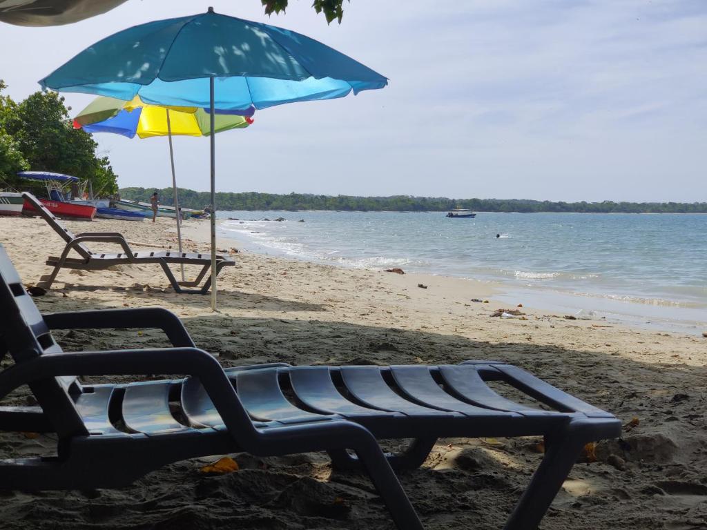 a beach with two chairs and an umbrella at Cabaña Villa Eugenia in Rincón
