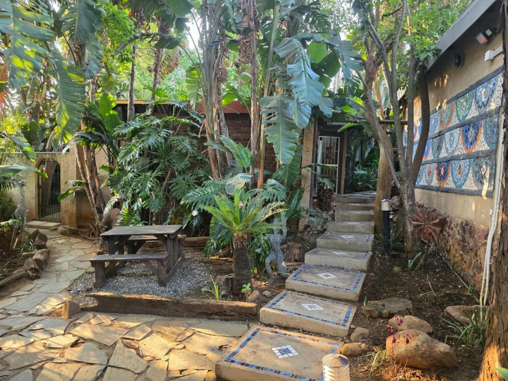 een tuin met een houten bank en een tafel bij The Pot in Pretoria