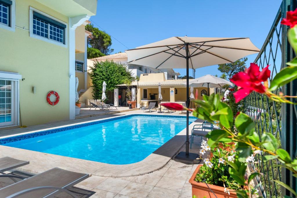 a swimming pool with an umbrella next to a building at MBird 19 Estoril Apartments in Estoril