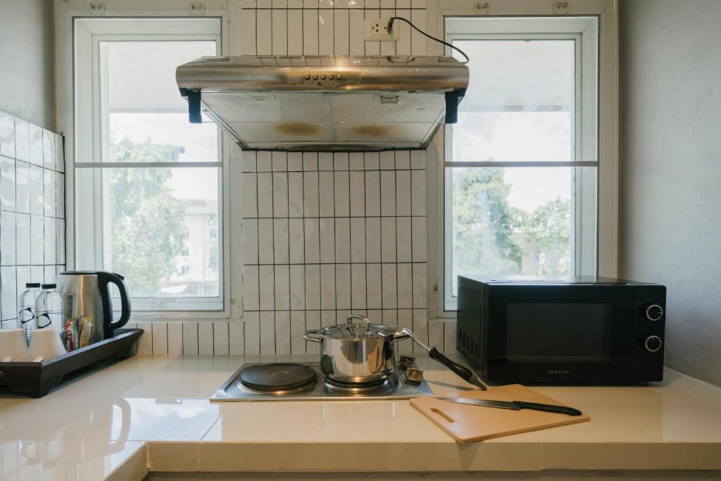 A compact kitchenette with a hotplate, microwave and electric kettle.