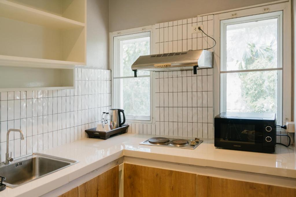 A compact kitchenette with a sink, hob, kettle and countertop oven.