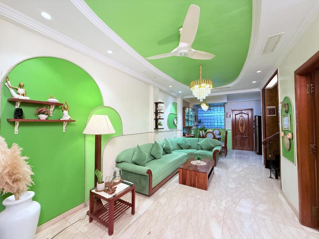 a living room with a green couch and green walls at Garden Veil Luxury Villa By Spacez in Mumbai