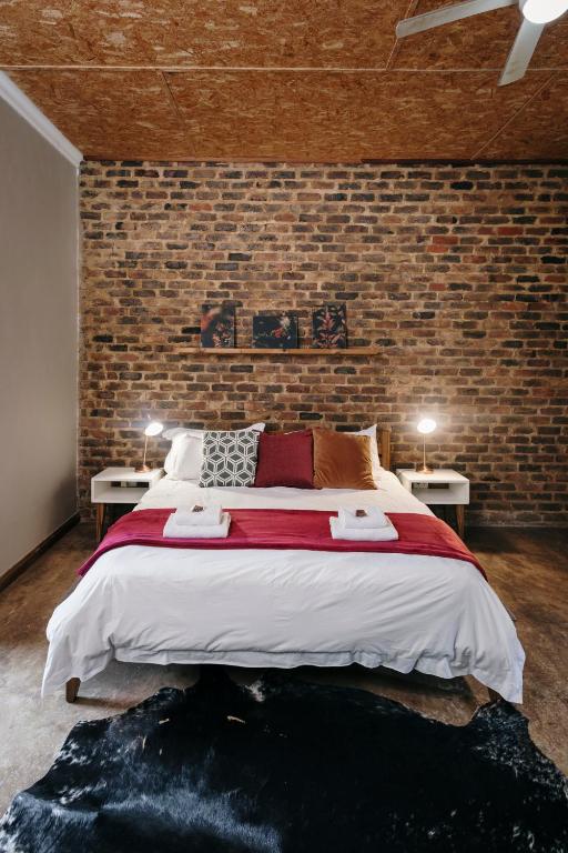 a bedroom with a large bed and a brick wall at Rosemary Hill Farm in Pretoria