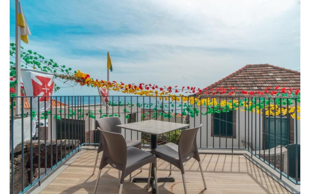 Un patio con una mesa y sillas en un balcón. en Éden Jardim Mar, en Jardim do Mar
