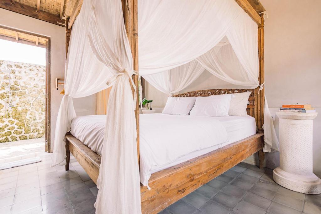 a bedroom with a canopy bed with a window at Bogen Nyitdah in Tabanan