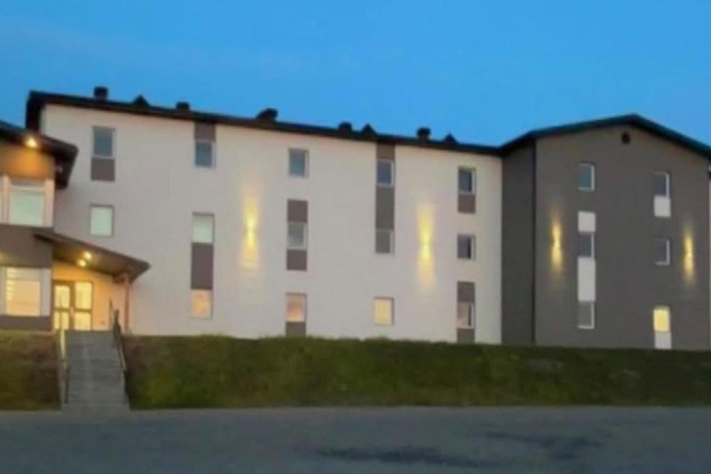 a large white building with windows at dusk at Auberge de la traverse in Matane