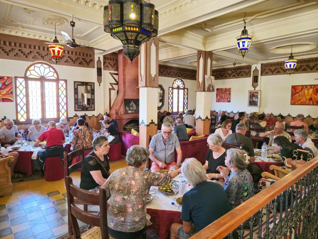 a group of people sitting at tables in a restaurant at Dromadaire Gourmand in Zagora