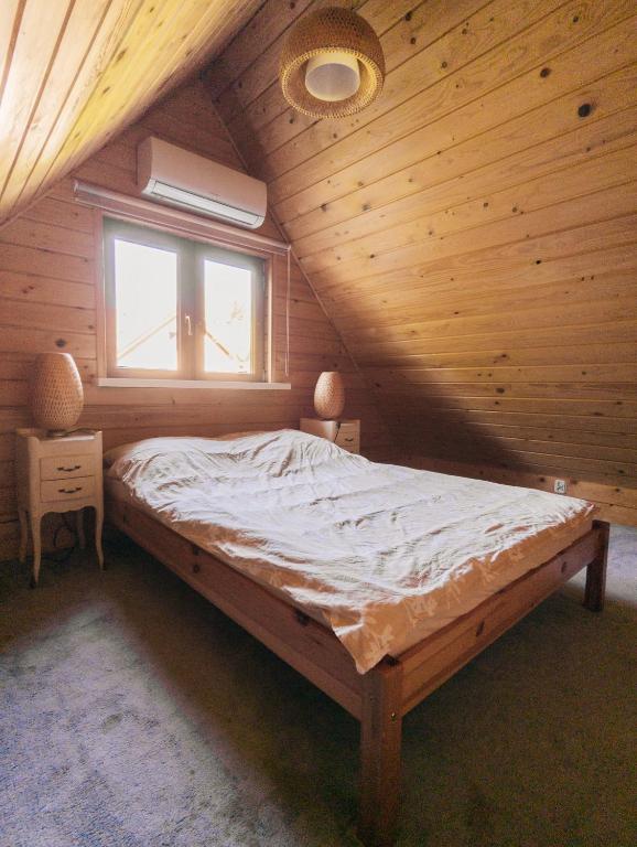 a large bed in a wooden room with a window at Domek Letniskowy na Wyłączność - Łaszka in Łaszka