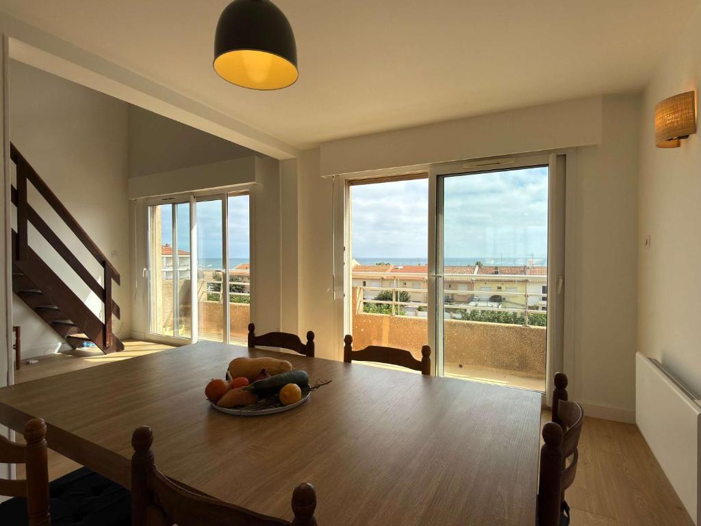 Sea view duplex في فالراس بلاج: غرفة طعام بها طاولة عليها وعاء من الفاكهة