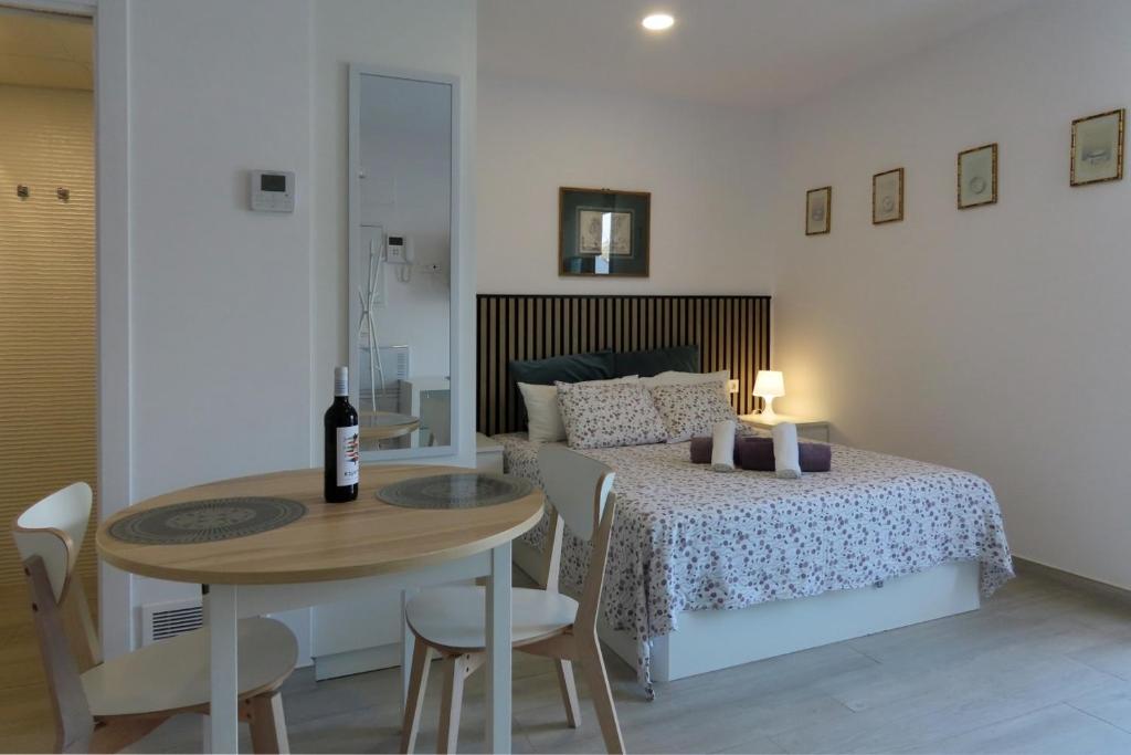 Un dormitorio con una cama y una mesa con una botella de vino en Sea Studio in La Cala de Mijas R, en Mijas Costa