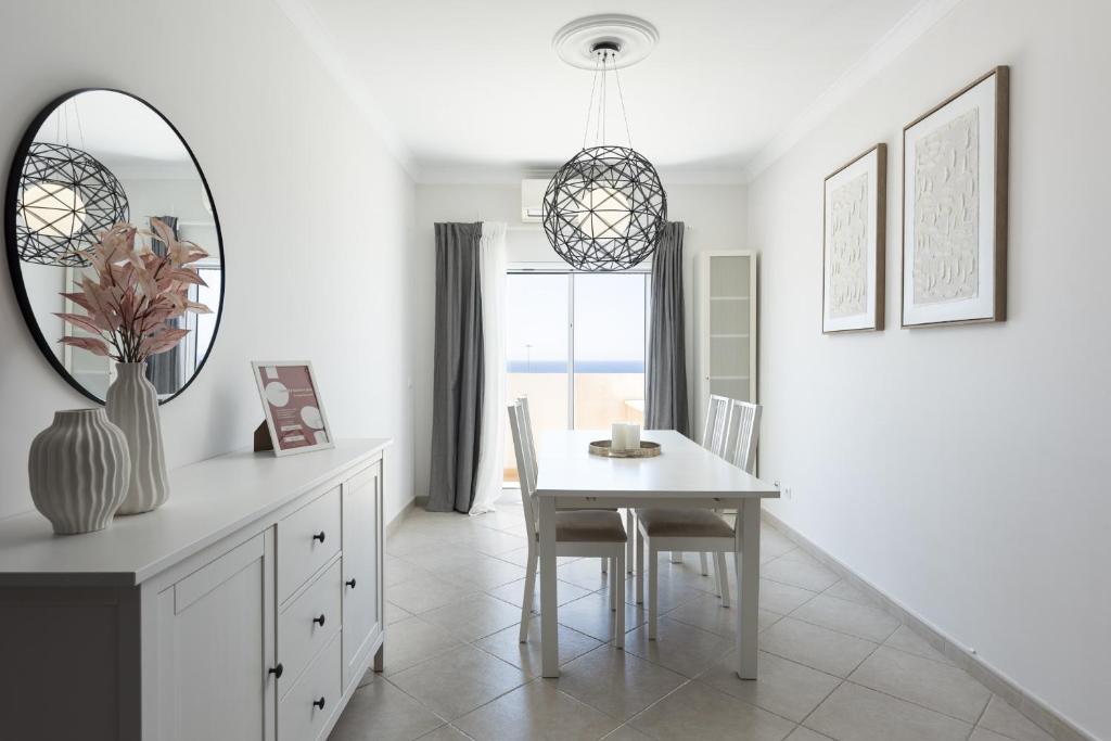a white dining room with a table and a mirror at Golfinho - Sea view with pool by HD in Quarteira