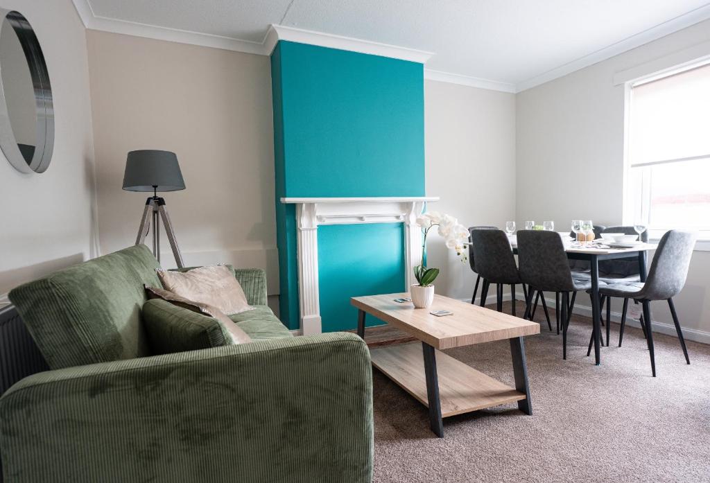 a living room with a green couch and a table at 3 BDR House At Caledonia Luxe Stays Short Lets & Serviced Accommodation Falkirk in Polmont