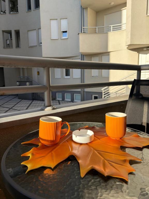 two coffee cups and a leaf on a table at Wing Apartman Jagodina in Jagodina