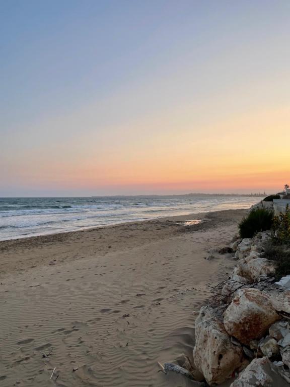 a beach with rocks and the ocean at sunset at Villa Marinella in Granelli