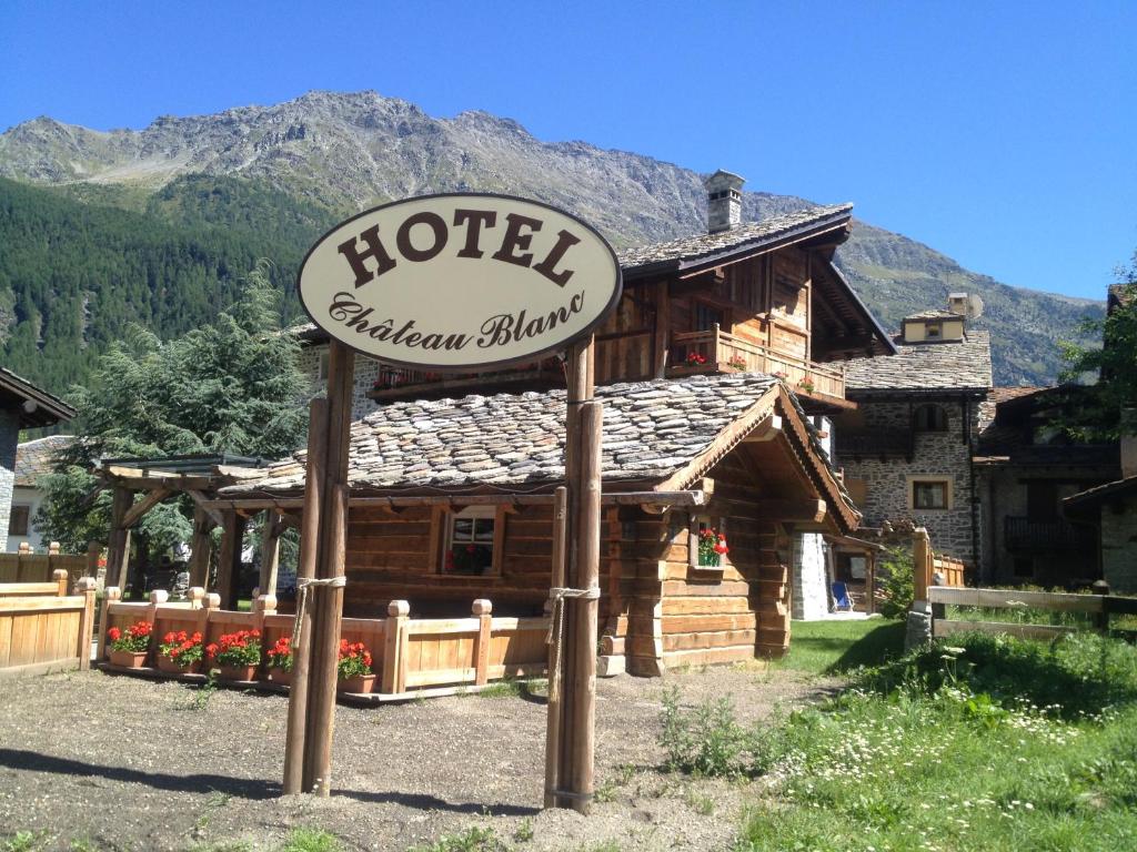 a hotel sign in front of a log cabin at Hotel Chateau Blanc in La Thuile