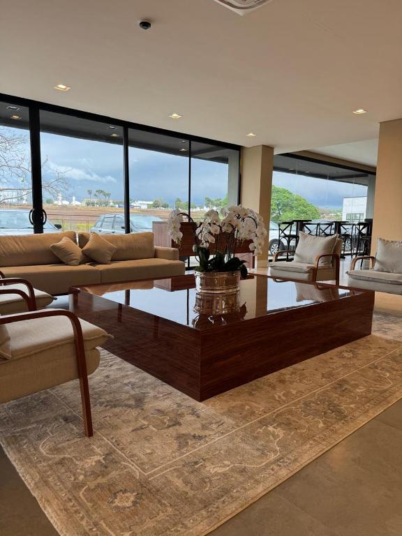 Una sala de estar con un sofá y una mesa con flores. en Hotel C jaguariuna, en Jaguariúna