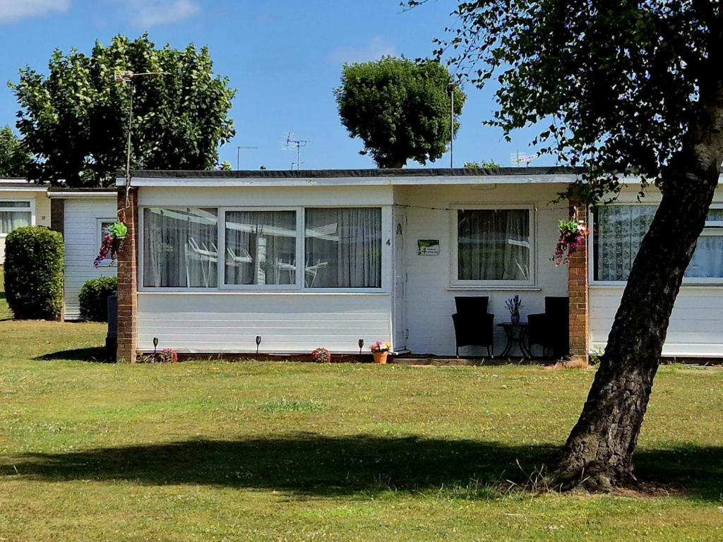 a white house with a tree in the yard at Roma's Retreat chalet, Hemsby in Hemsby