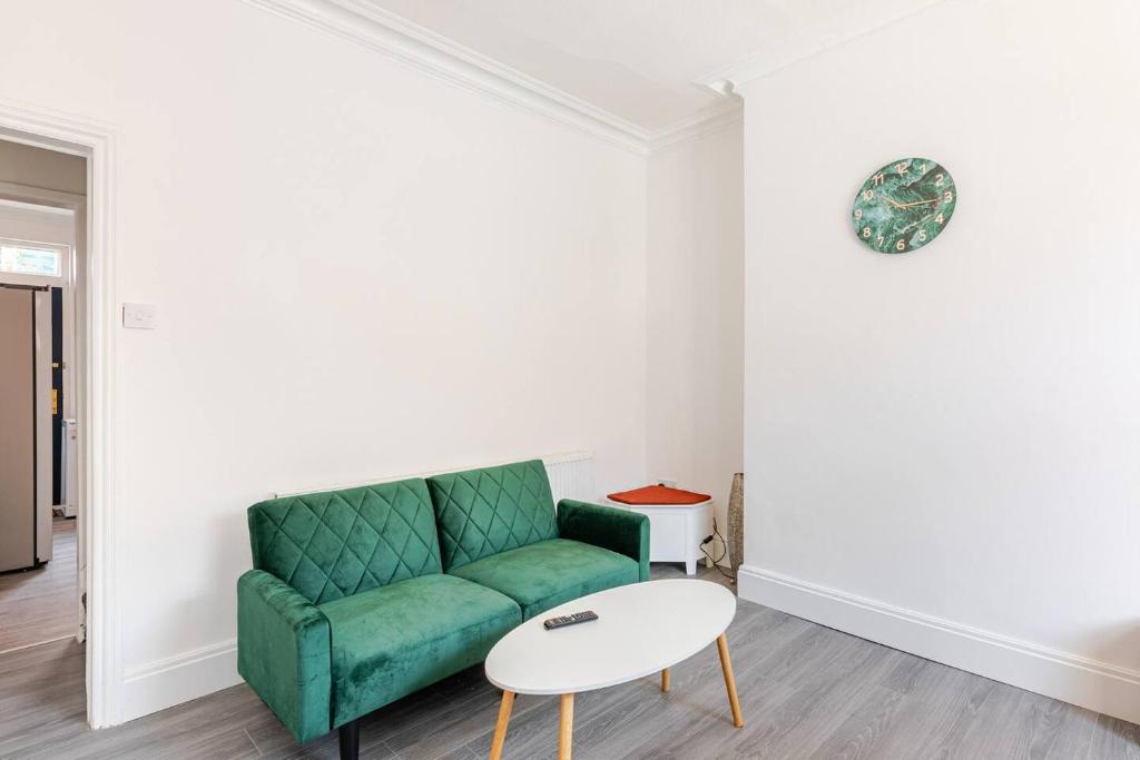 a living room with a green couch and a table at Burley Guest House in Headingley