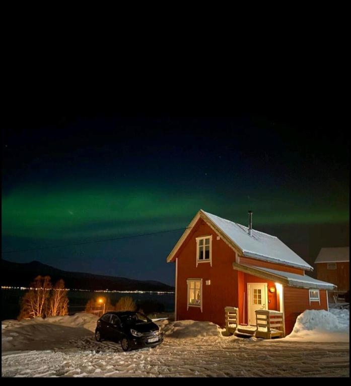 a car parked in front of a house with the northern lights at Rødstua in Senja