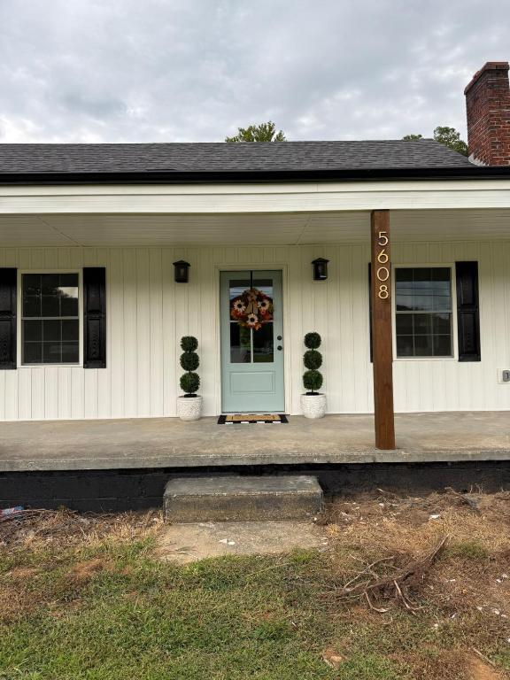 a house with a blue door and two plants at Juanitas Garden Cottage in Jonesville