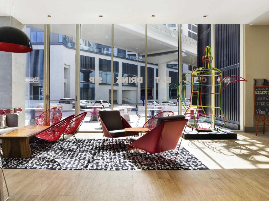 a lobby with chairs and a table and a large vase at ibis Styles Dubai Airport Hotel in Dubai