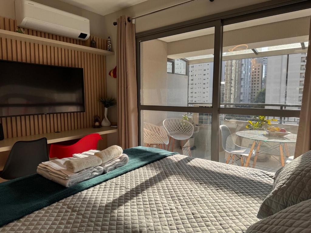 ein Schlafzimmer mit einem Bett und ein Balkon mit einem Tisch in der Unterkunft Flat em Moema Grand Vitrali - Aero Congonhas in São Paulo