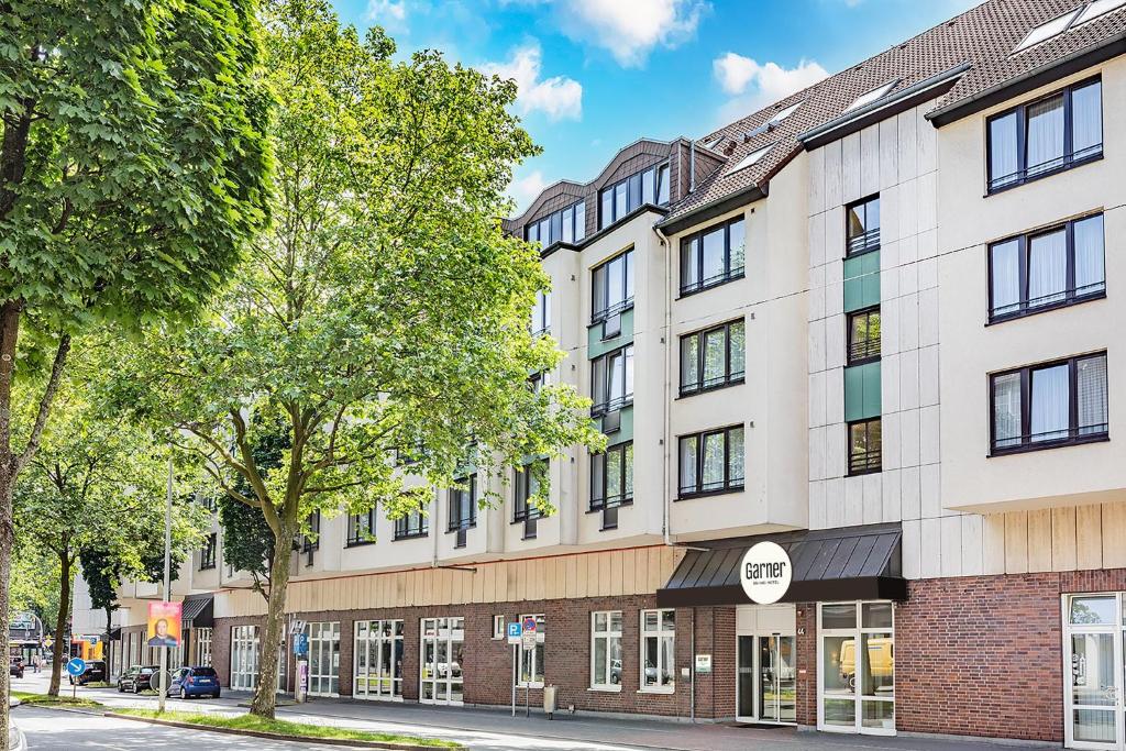 an apartment building on a street with trees at Garner Hotel Bochum by IHG in Bochum