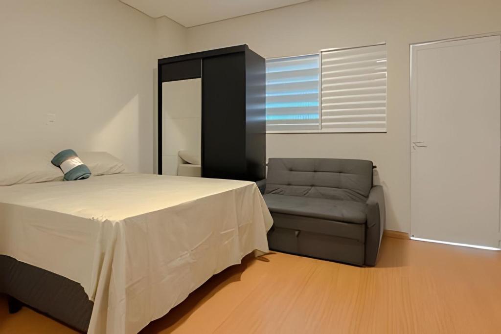 um quarto com uma cama e uma cadeira em Flats_Sabia em Uberlândia