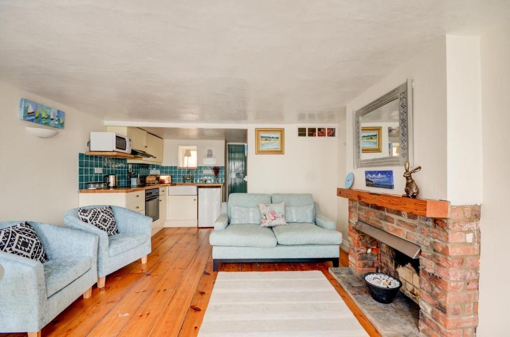 a living room with two chairs and a fireplace at Tern Cottage in Wells next the Sea