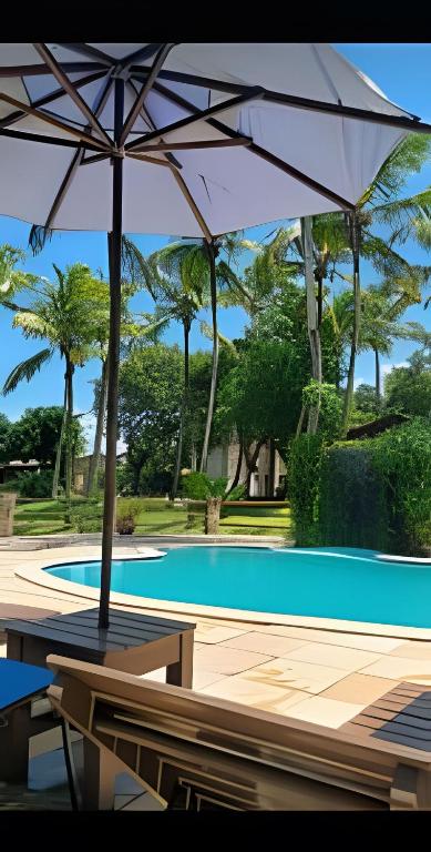 a table with an umbrella next to a swimming pool at Porto do Sol - Chalé 25 in Pipa