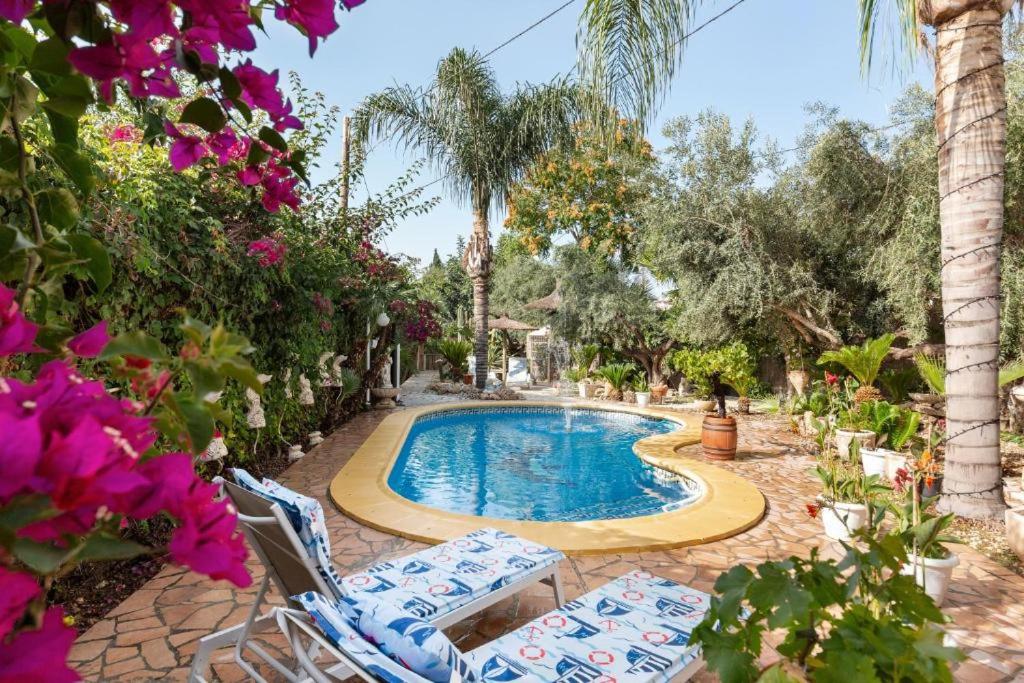 a swimming pool with two lawn chairs and flowers at Casa-Villa en Lorca relax vistas y piscina privada in Lorca