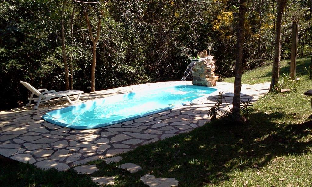 uma piscina num quintal com uma cadeira em Pousada Da Mata em Pirenópolis