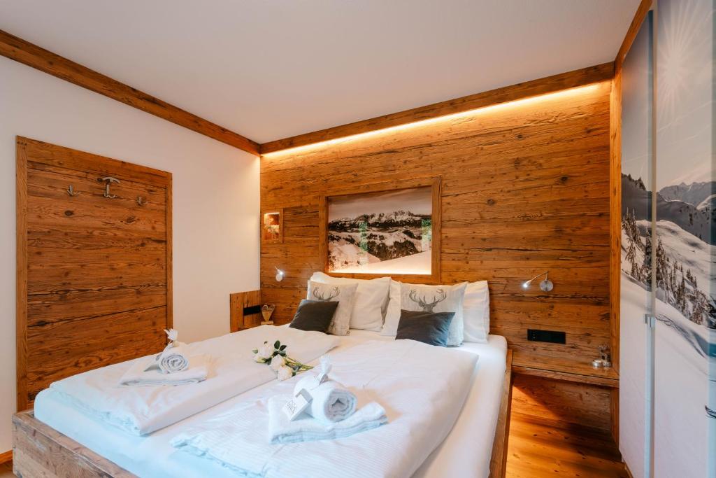 a bedroom with a large white bed with a wooden wall at TraumChalet mit Sauna in Kirchberg im Skigebiet Kitzbühel in Kirchberg in Tirol