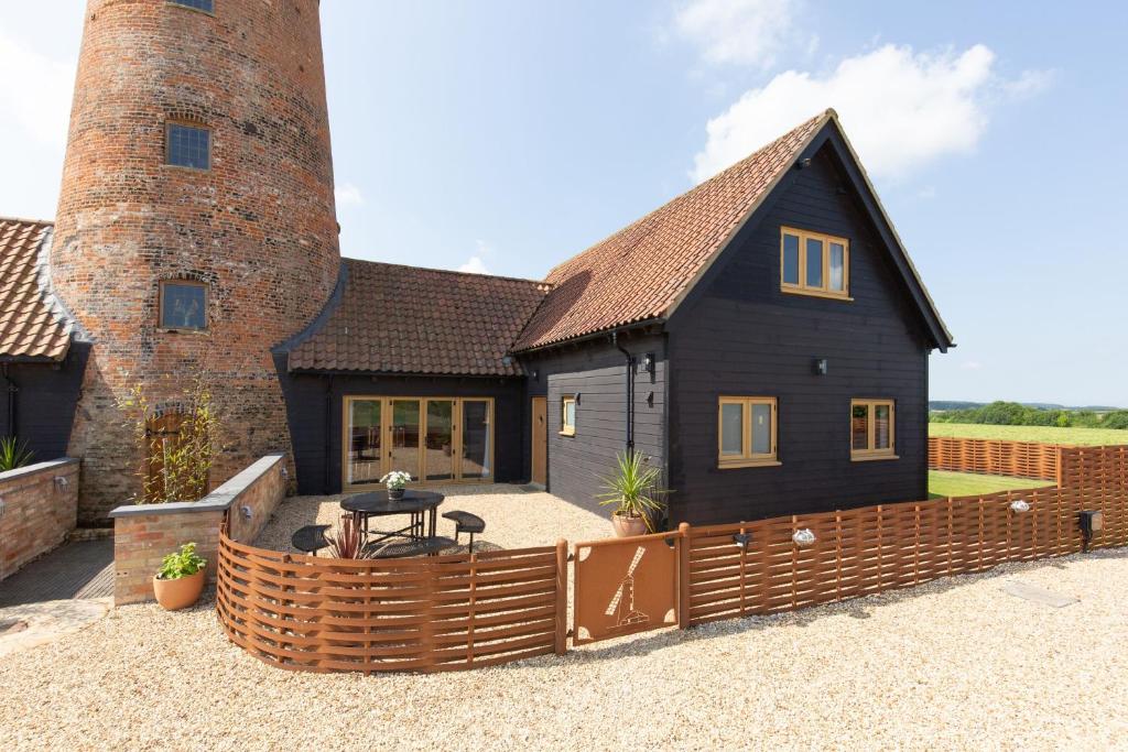 a black house with a wooden fence in front of it at Fantail in Harpley
