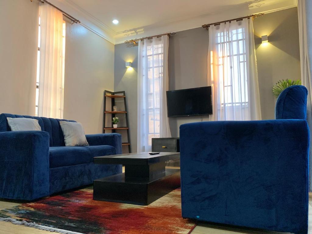 a living room with two blue couches and a coffee table at WanderHome 1BDR in Kampala