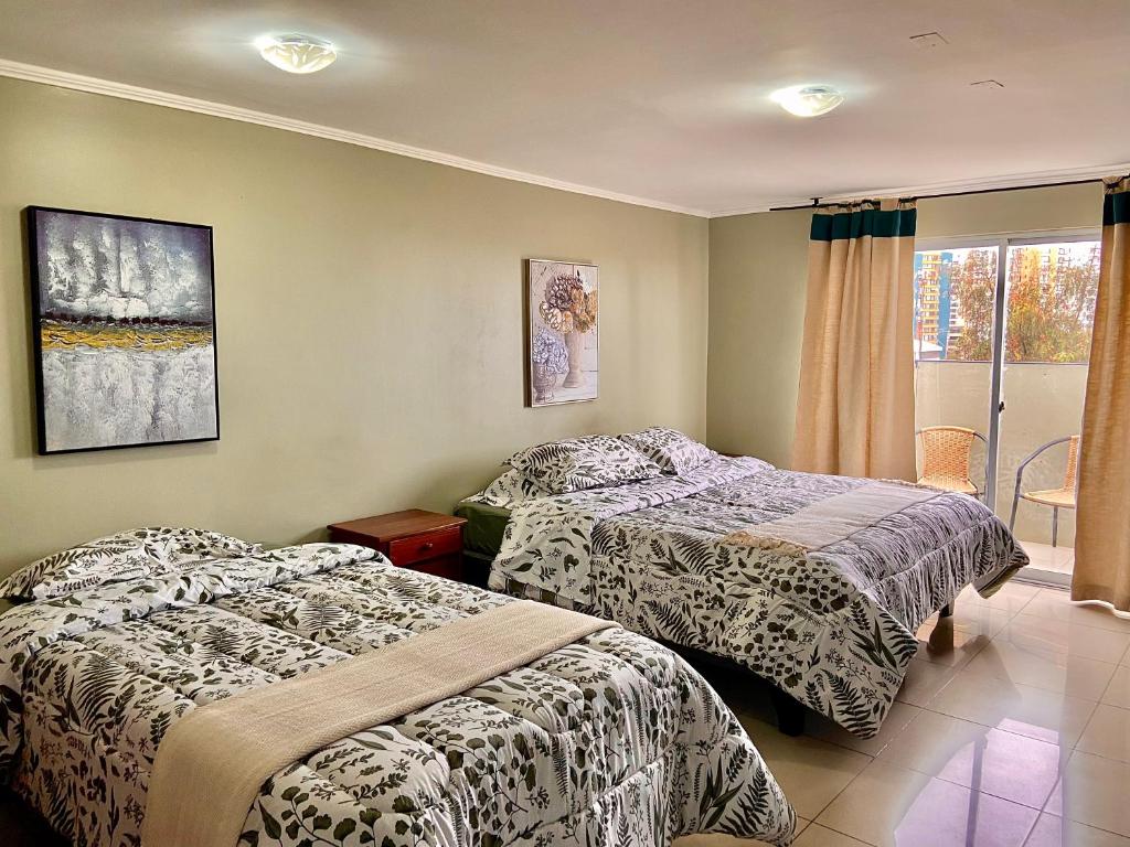 a bedroom with two beds and a window at Hotel Khantati in Iquique