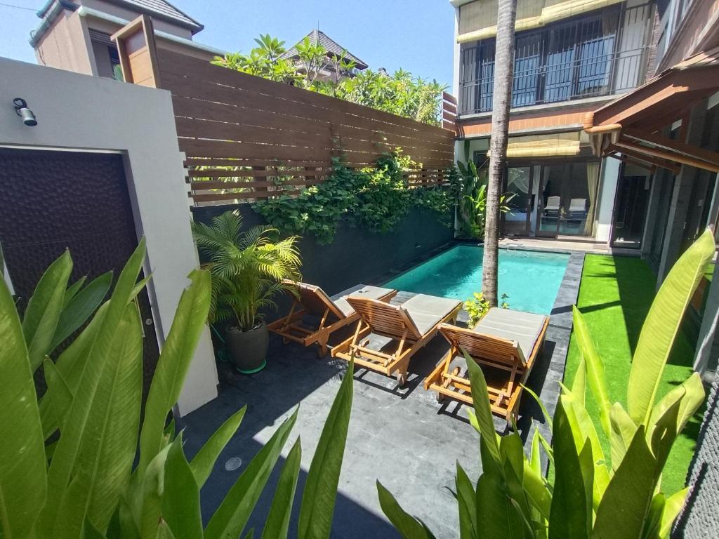 a patio with chairs and a swimming pool at Villa CUCU - Legian - 3 Bedroom in Legian