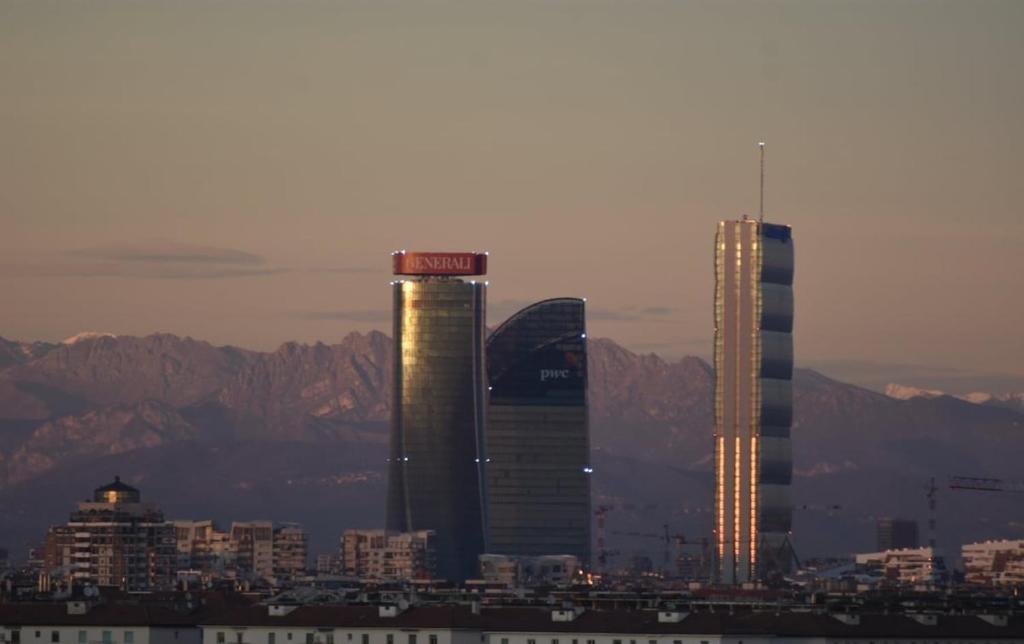 two tall buildings in a city with mountains in the background at Mountain View Room in Milan