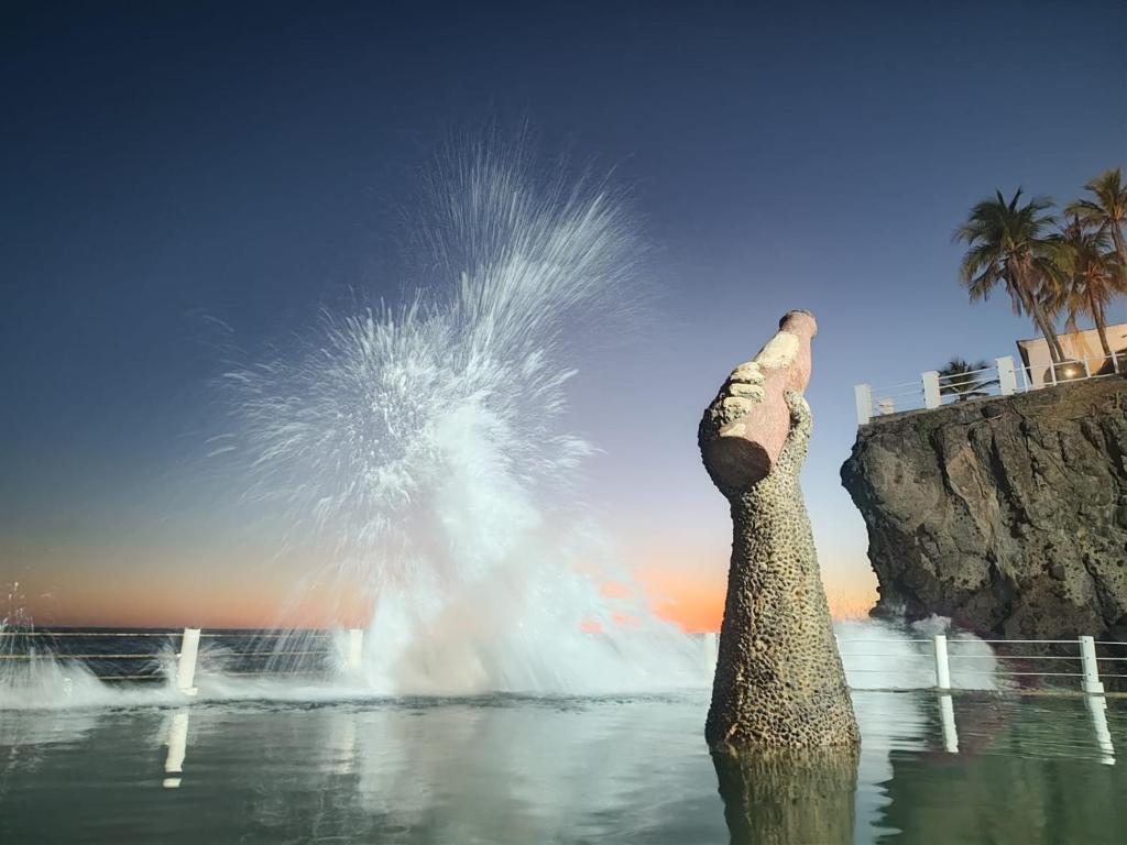 a fountain in the water with a persons foot in the air at Cadejo Brewing Company El Sunzal in Tamanique