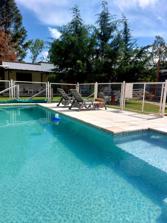 a swimming pool with two chairs next to a fence at Ideal Alojamiento in Lunlunta